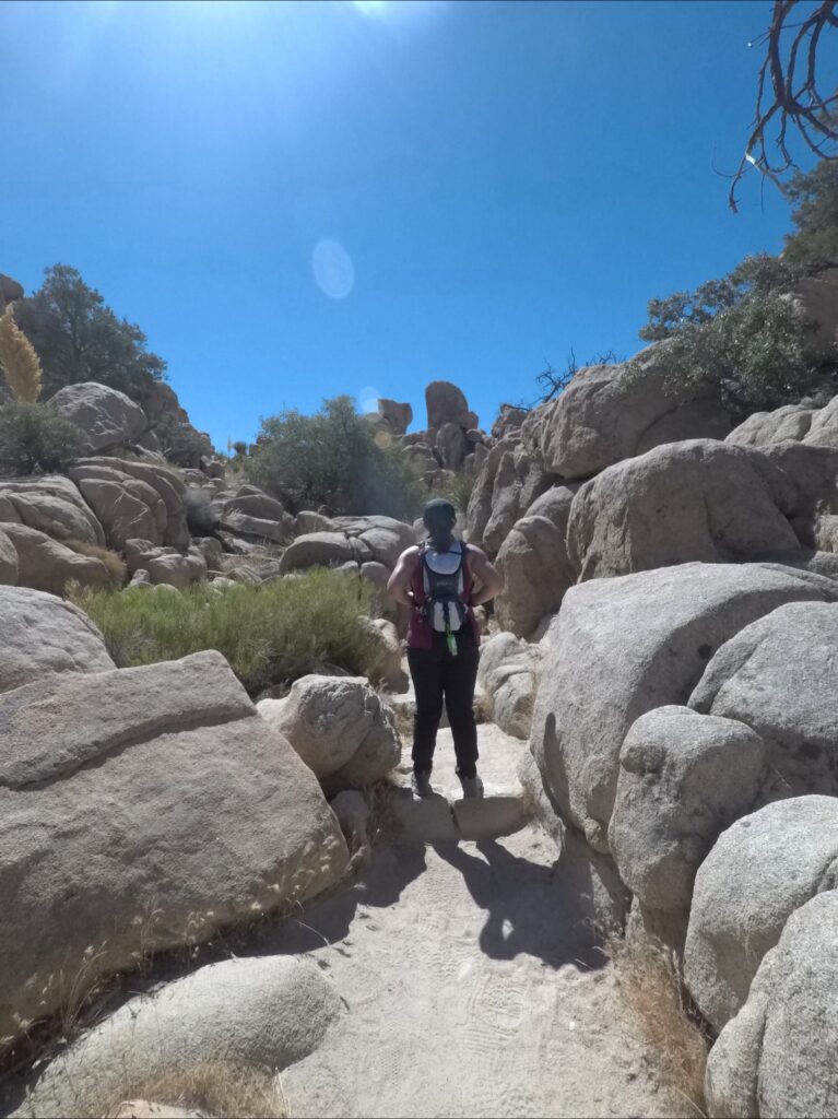 GPTempDownload Back of a woman wearing a backpack standing in between rocks
