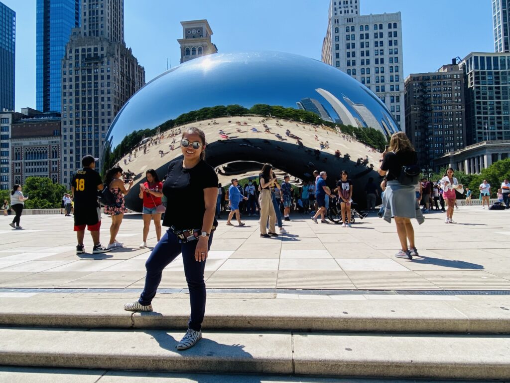 Visitors in front of a silver sculpture shaped like a bean in Chicago.