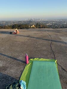 green yoga mat and bottle on a helipad with the view of downtown los angeles