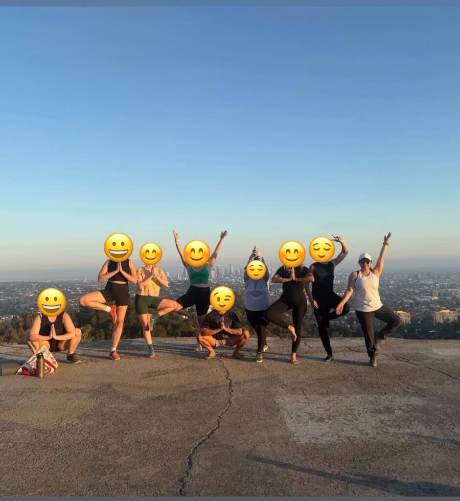 9 people in different yoga poses with downtown los angeles in the background
