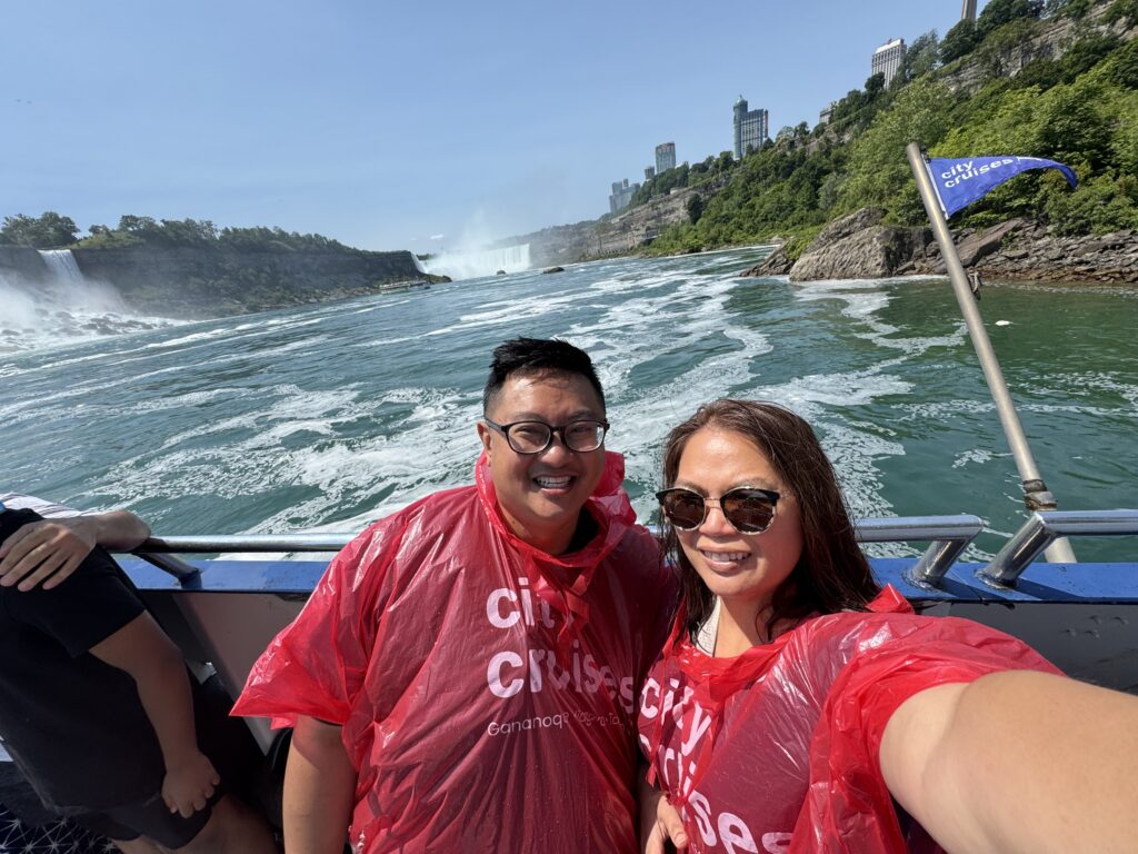 man and woman wearing a red city cruises poncho with niagara falls in the background