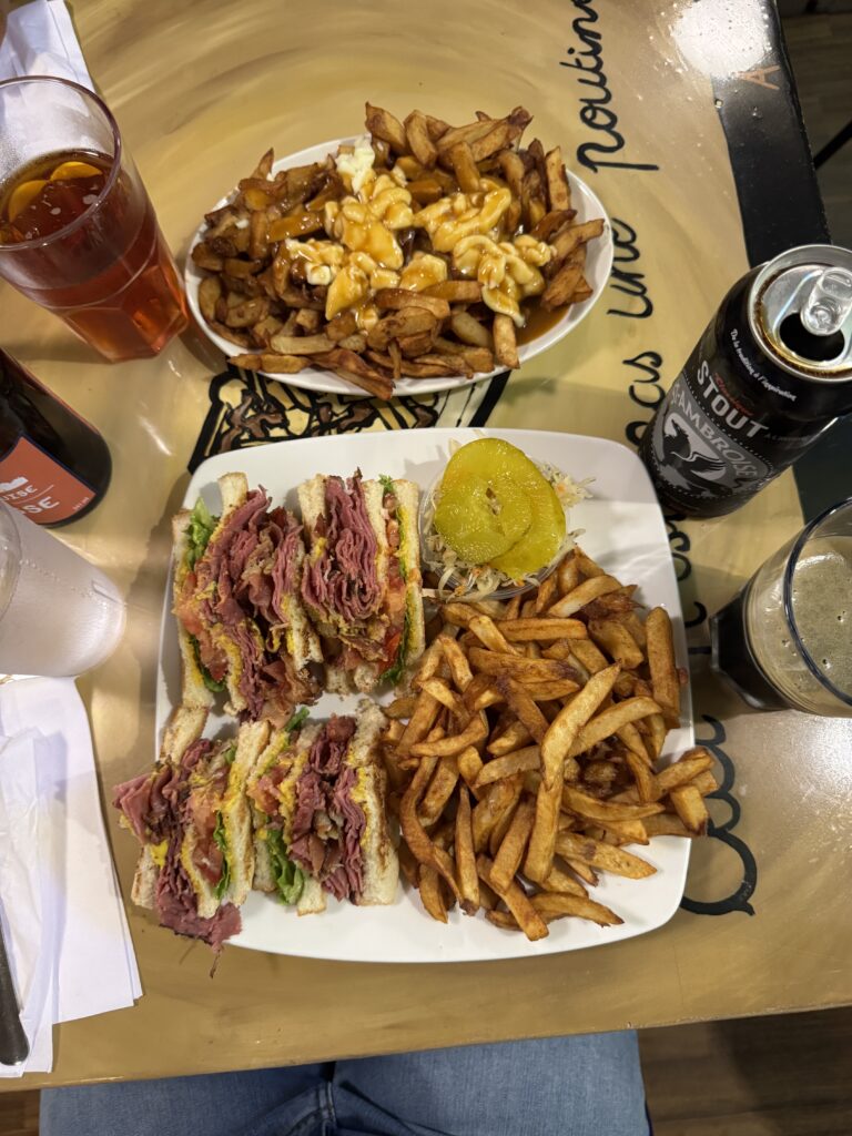 table with poutine, sandwich fries and beer