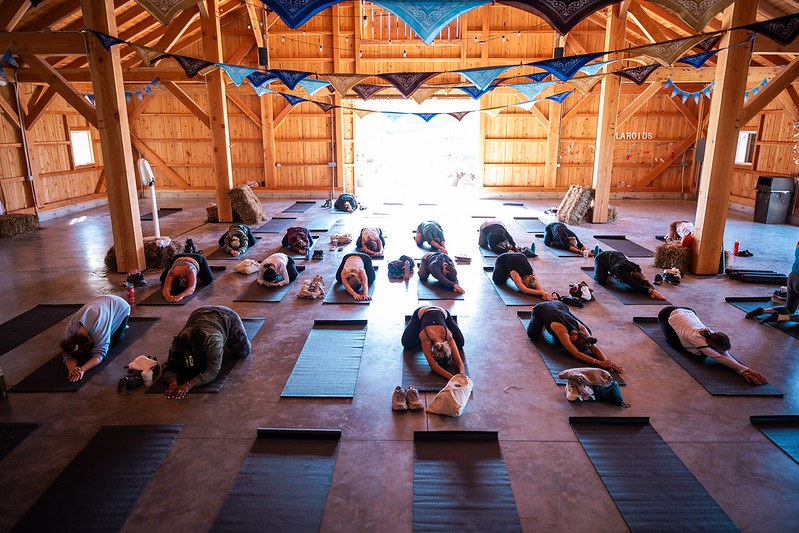 women in yoga child's pose in a barn.