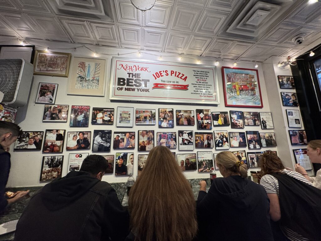 Inside Joe's Pizza with wall full of photos of celebrities