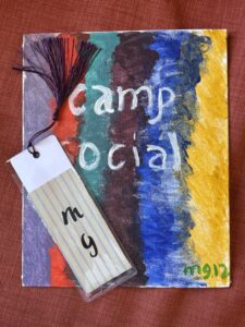 small canvas painted that ssays camp social and a bookmark with initials MG