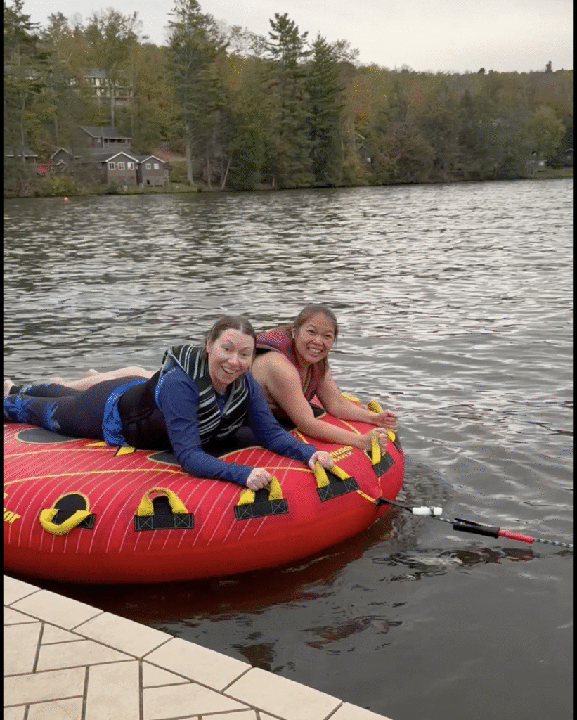two women holding on an inflatable with handles on a lake