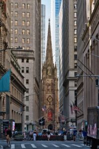 Iconic Trinity Church framed by towering skyscrapers in New York City, blending historic and modern architecture.