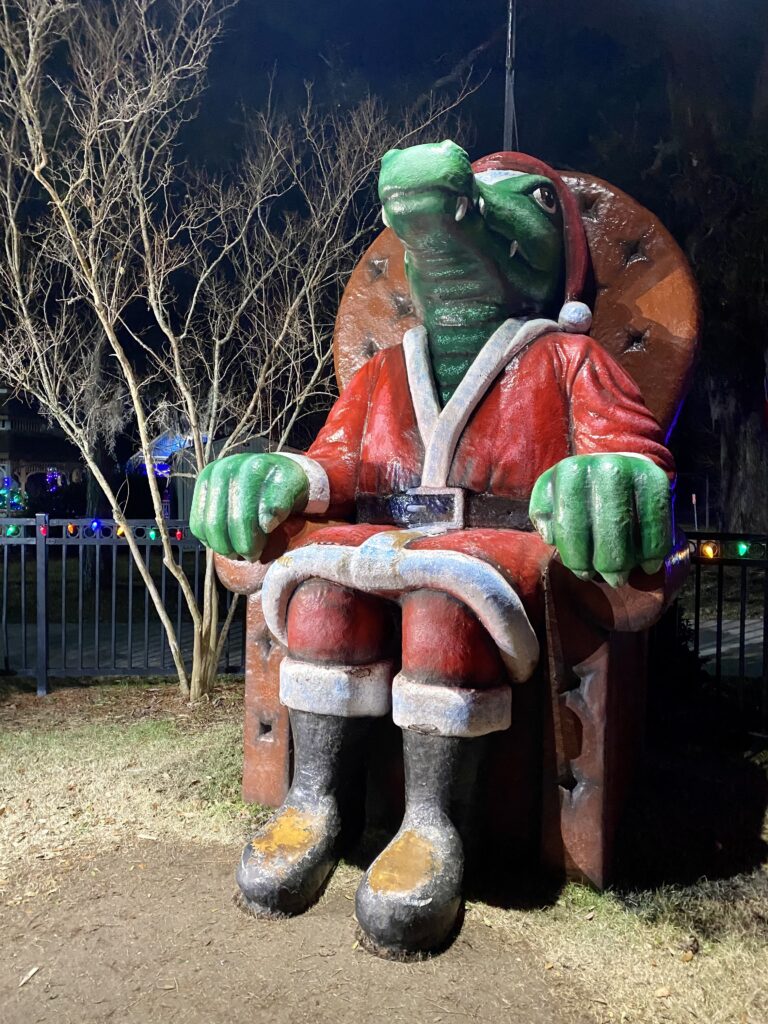 big statue of an alligator dressed in Santa Claus outfit sitting on a chair