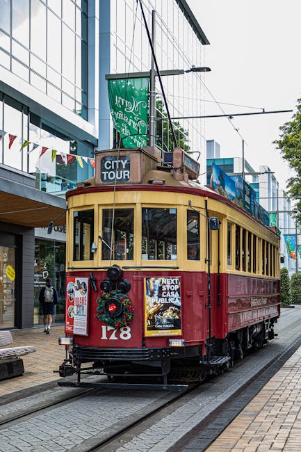 A classic red and yellow tram travels through a bustling urban area on a city tour.